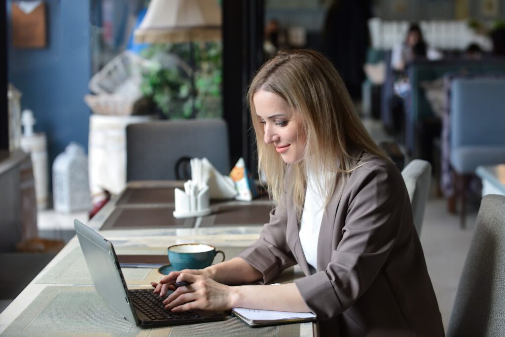 A Woman In Front Of Her Laptop Writing A Resume At Coffee Shop