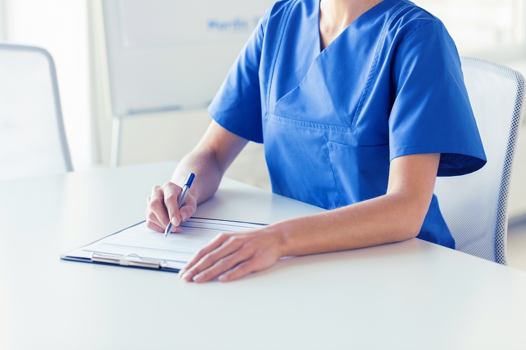 A Registered Nurse Writing On A Clipboard